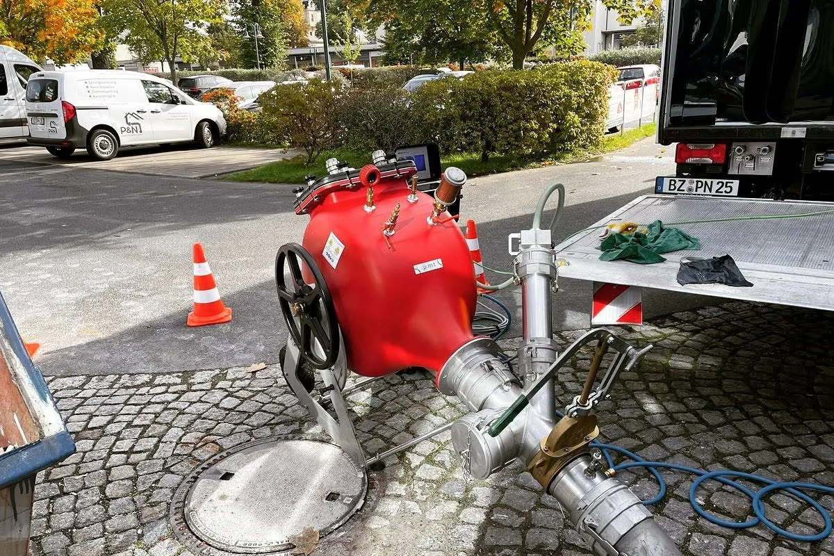 Geöffneter Schacht im Kopfsteinpflaster mit der Technik, über die ein Schlauchliner in die Leitung eingebracht wird